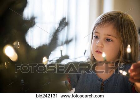 Caucasian girl hanging lights on Christmas tree View Large Photo Image Stock Image - Caucasian girl hanging lights on Christmas tree. Fotosearch