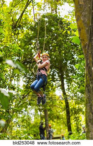 Caucasian girl hanging on zip line in forest View Large Photo Image Stock Photo - Caucasian girl hanging on zip line in forest. Fotosearch