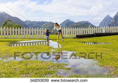 Caucasian girl helping brother standing in puddle View Large Photo Image Stock Photo - Caucasian girl helping brother standing in puddle. Fotosearch