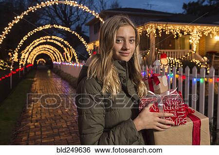 Stock Photograph - Caucasian girl holding Christmas gifts on sidewalk. Fotosearch