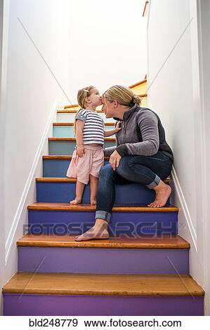 Caucasian girl kissing mother on forehead on multicolor staircase View Large Photo Image Stock Photo - Caucasian girl kissing mother on forehead on multicolor staircase. Fotosearch