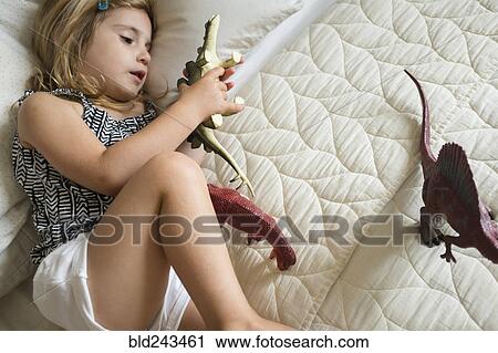 Caucasian girl laying on bed playing with toy dinosaurs View Large Photo Image Stock Image - Caucasian girl laying on bed playing with toy dinosaurs. Fotosearch