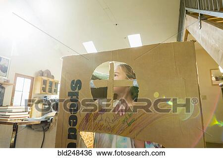 Stock Photograph - Caucasian girl playing in cardboard house. Fotosearch