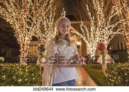 Picture - Caucasian girl posing near Christmas decorations in yard. Fotosearch