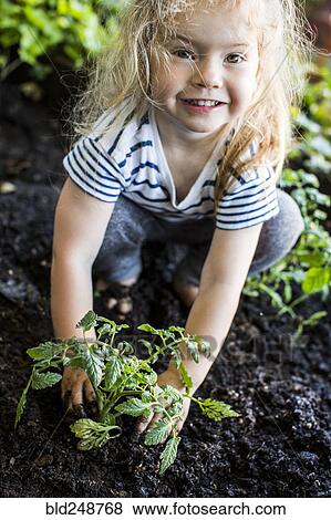 Caucasian girl posing with plant in garden View Large Photo Image Stock Photo - Caucasian girl posing with plant in garden. Fotosearch