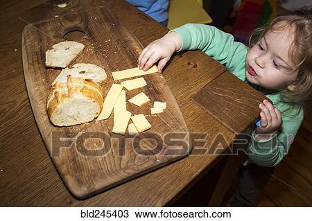 Caucasian girl reaching for cheese near bread on cutting board View Large Photo Image Stock Image - Caucasian girl reaching for cheese near bread on cutting board. Fotosearch