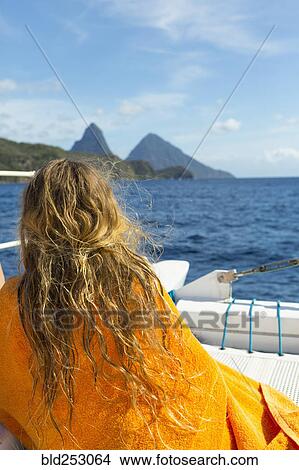Picture - Caucasian girl sitting on boat wrapped in a towel. Fotosearch
