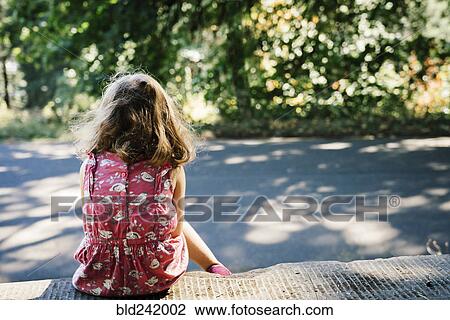 Stock Image - Caucasian girl sitting on curb. Fotosearch