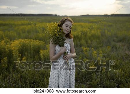 Stock Photo - Caucasian girl standing in field holding bouquet of wildflowers. Fotosearch