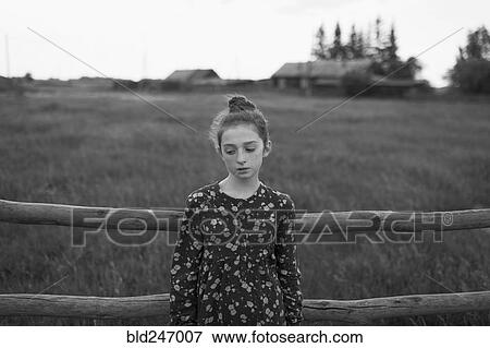 Stock Photo - Caucasian girl standing near wooden fence. Fotosearch