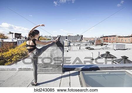 Caucasian girl stretching leg on rooftop View Large Photo Image Stock Photography - Caucasian girl stretching leg on rooftop. Fotosearch