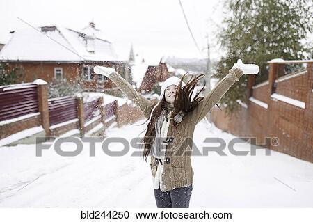 Stock Image - Caucasian girl throwing snow outdoors. Fotosearch