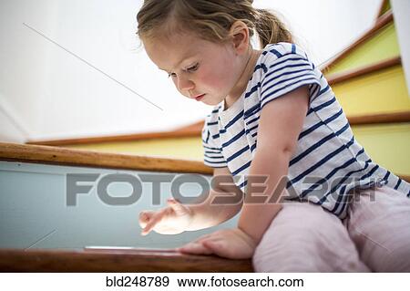 Stock Photo - Caucasian girl using digital tablet on staircase. Fotosearch