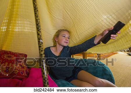 Picture - Caucasian girl using remote control in blanket fort. Fotosearch