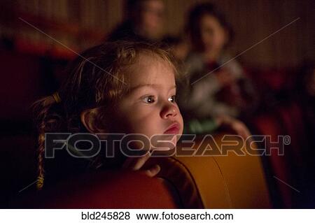 Stock Photo - Caucasian girl watching movie in theater. Fotosearch