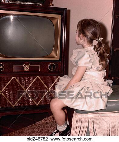 Stock Image - Caucasian girl watching vintage television. Fotosearch