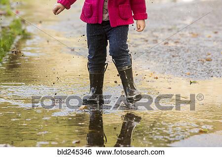 Caucasian girl wearing boots splashing in puddle View Large Photo Image Stock Photograph - Caucasian girl wearing boots splashing in puddle. Fotosearch