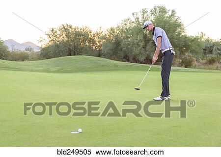 Stock Photography - Caucasian golfer putting on golf course. Fotosearch