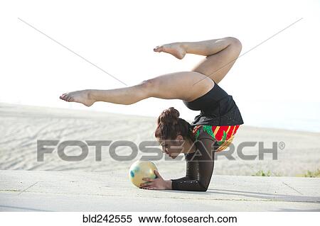 Stock Photography - Caucasian gymnast balancing on arms on beach. Fotosearch