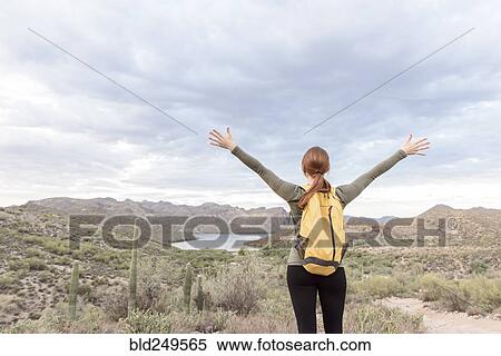 Stock Photography - Caucasian hiker standing with arms raised in desert. Fotosearch