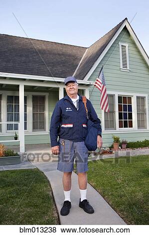 Stock Photo - Caucasian mailman standing in front yard. Fotosearch