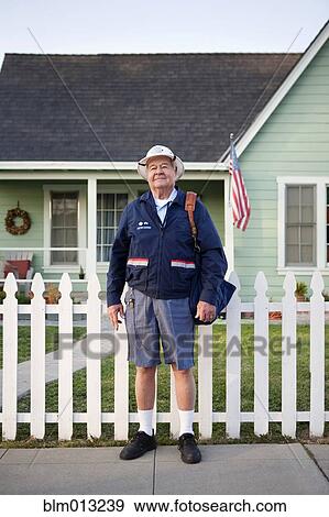 Stock Photo - Caucasian mailman standing on sidewalk. Fotosearch