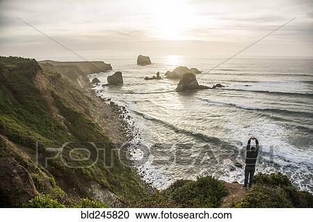 Caucasian man admiring scenic view of ocean sunset stretching arms View Large Photo Image Stock Image - Caucasian man admiring scenic view of ocean sunset stretching arms. Fotosearch