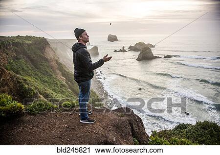 Stock Image - Caucasian man admiring scenic view of ocean sunset. Fotosearch