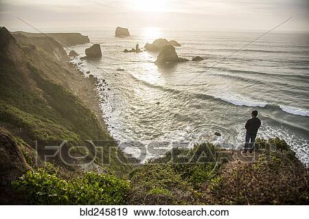 Caucasian man admiring scenic view of ocean sunset View Large Photo Image Stock Photo - Caucasian man admiring scenic view of ocean sunset. Fotosearch