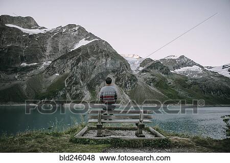 Stock Photo - Caucasian man admiring scenic view of mountain lake. Fotosearch