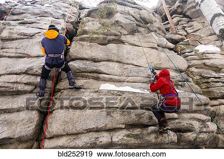 Stock Photo - Caucasian man and woman rock climbing. Fotosearch
