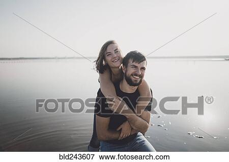 Caucasian man carrying woman piggyback on beach View Large Photo Image Stock Photo - Caucasian man carrying woman piggyback on beach. Fotosearch