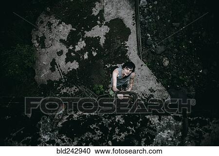 Caucasian man climbing ladder in concrete alley View Large Photo Image Stock Image - Caucasian man climbing ladder in concrete alley. Fotosearch