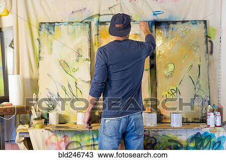 Stock Image - Caucasian man creating paintings. Fotosearch
