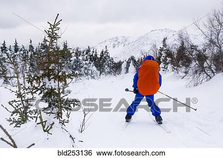 Stock Photograph - Caucasian man cross-country skiing near mountain. Fotosearch