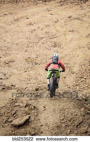 Stock Image - Caucasian man descending dirt trail on bicycle. Fotosearch