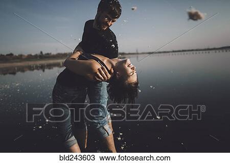 Stock Image - Caucasian man dipping woman at lake. Fotosearch
