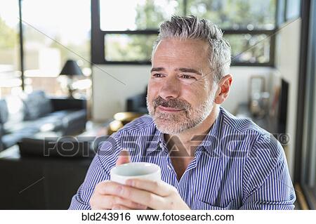 Stock Photograph - Caucasian man drinking coffee and daydreaming. Fotosearch