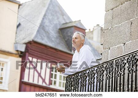 Caucasian man drinking coffee on balcony in city View Large Photo Image Stock Image - Caucasian man drinking coffee on balcony in city. Fotosearch