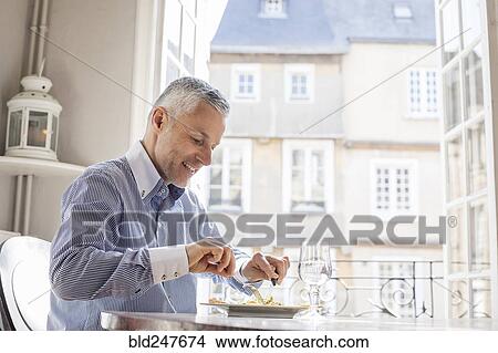Picture - Caucasian man eating meal. Fotosearch