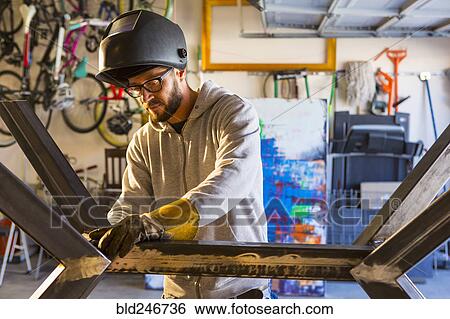 Stock Photograph - Caucasian man examining metal sculpture. Fotosearch