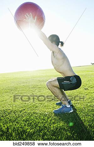 Caucasian man exercising with fitness ball in sunny field View Large Photo Image Stock Photo - Caucasian man exercising with fitness ball in sunny field. Fotosearch