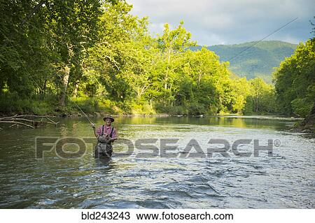 Stock Image - Caucasian man fishing in river. Fotosearch