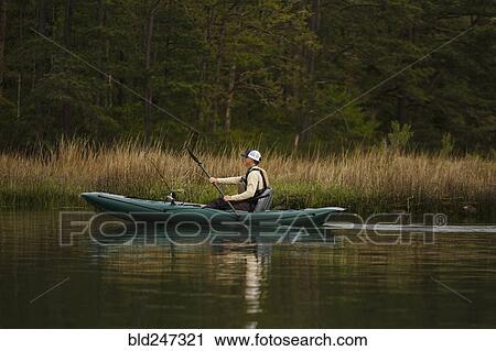 Stock Image - Caucasian man fishing on kayak. Fotosearch
