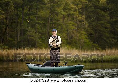 Stock Image - Caucasian man fishing on kayak. Fotosearch