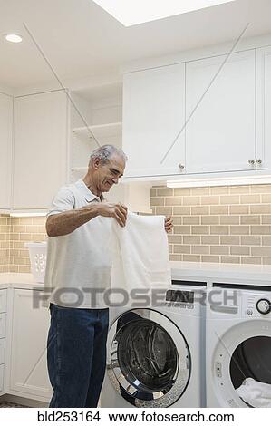 Caucasian man folding towel in modern laundry room View Large Photo Image Picture - Caucasian man folding towel in modern laundry room. Fotosearch