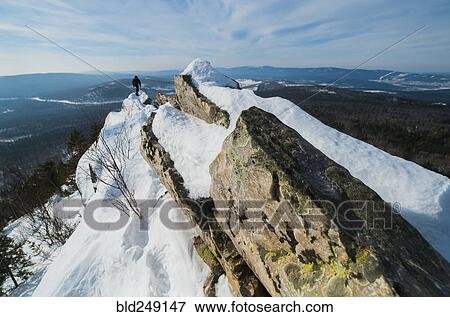 Stock Photo - Caucasian man hiking on mountain in winter. Fotosearch