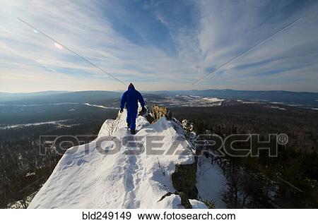 Stock Photo - Caucasian man hiking on mountain top in winter. Fotosearch
