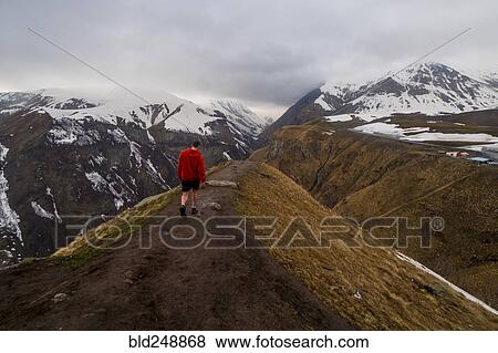 Stock Photo - Caucasian man hiking on snowy Mountain. Fotosearch