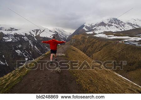 Stock Photo - Caucasian man hiking on snowy Mountain. Fotosearch